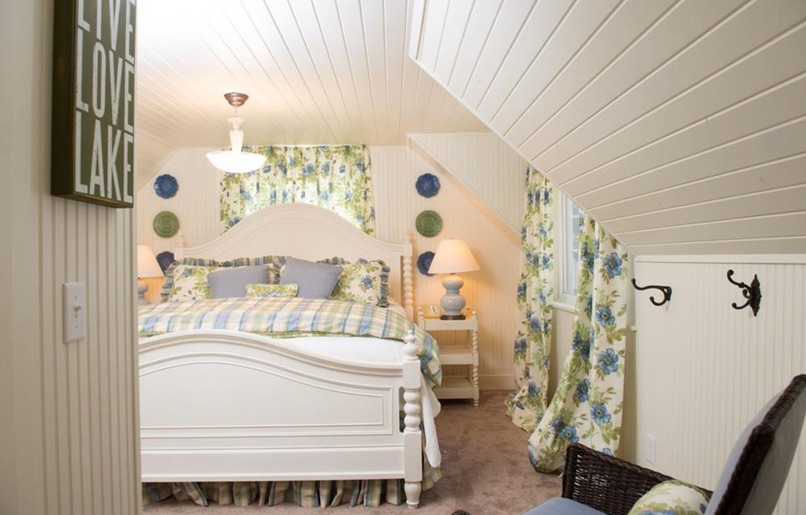 Layered blue, green and white guest bedroom beneath a sloped ceiling