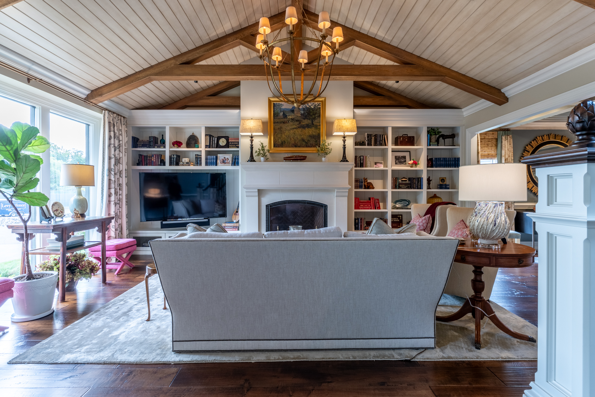 Mallard Cove great room with exposed beams, built-in bookshelves and a white fireplace